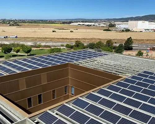 Photovoltaikanlage auf einem Dach eines Hauses mit Innenhof, braune Felder im Hintergrund (Foto)