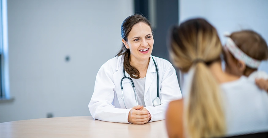 Eine Ärztin berät eine Patientin, die ihr Kind im Arm hält (Foto)