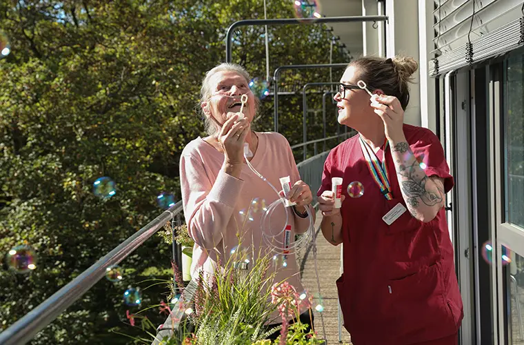 Carer and resident of a retirement home making soap bubbles (Photo)